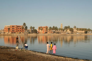people standing on the banks of a river in Saint Louis, Senegal