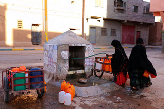 In photo taken Thursday Oct.19, 2017 Moroccan women fill up containers with water from a hose, in Zagora, southeastern Morocco. Experts blame poor choices in agriculture, growing populations and climate change for the water shortages in towns like Zagora, which has seen repeated protests for access to clean water in recent weeks. Since the summer, taps ran dry in Zagora. (AP Photo/ Issam Oukhouya)