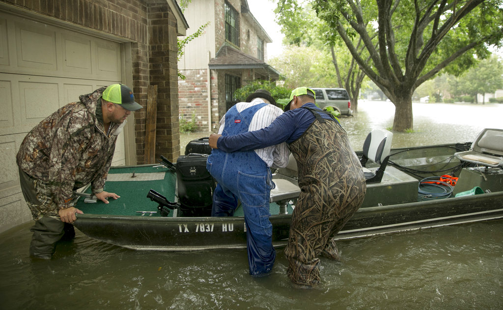 Thomas Luna, left, and Hugo Elizonda, right, rescue Bobby Nelson, 78, from his flooded home in the Ravensway neighborhood in northwest Houston after Hurricane Harvey, Monday, Aug. 28, 2017. Luna and Elizondo came with a fishing boat to help with the rescue effort. (Jay Janner/Austin American-Statesman via AP)