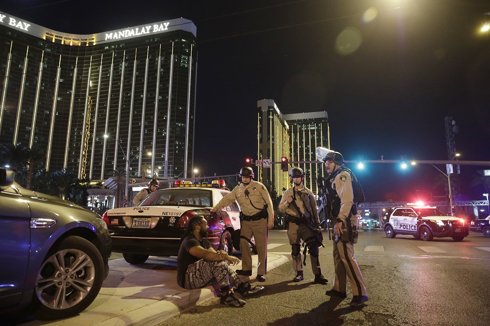 Police officers stand at the scene of a shooting near the Mandalay Bay resort and casino on the Las Vegas Strip, Sunday, Oct. 1, 2017, in Las Vegas. Multiple victims were being transported to hospitals after a shooting late Sunday at a music festival on the Las Vegas Strip. (AP Photo/John Locher)
