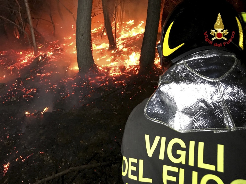 A firefighter hoses down a fire near Varese, northern Italy, early Monday, Oct. 30, 2017. Switzerland is sending three helicopters to help Italian fire crews try to extinguish forest fires that have been scorching parts of northern Italy for days and forced the evacuation of hundreds of people. Authorities in Piemonte and Lombardy are seeking to have a state of emergency declared for their regions, which have been hit by an abnormally dry summer, little rainfall and winds that have helped spread the flames. The smoke has contributed to a huge cloud of smog, visible from space, that has covered the region for days. (Vigili del Fuoco/Italian Firefighters via AP)