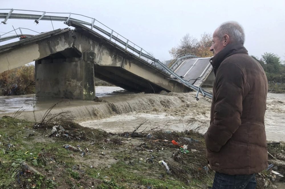Local resident Nue Shkreta looks at a collapsed bridge at the entrance of his village Mamuras, northern Albania, Friday, Dec. 1, 2017. At least one person has died during heavy rainfall that flooded many parts of Albania, paralyzing its ports and causing flights from its only international airport to be suspended, authorities said Friday. (AP Photo/Florent Bajrami)