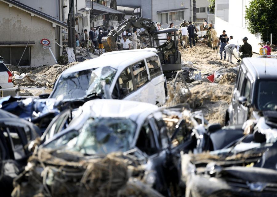 Cars are trapped in mud as residents clean up after days of heavy rain hit southwestern Japan, in Hiroshima city, southwestern Japan, Tuesday, July 10, 2018. Rescuers were combing through mud-covered hillsides and along riverbanks Tuesday searching for dozens of people missing after heavy rains unleashed flooding and mudslides in southwestern Japan. (Ryosuke Ozawa/Kyodo News via AP)